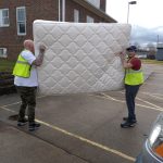 Two community service volunteers help move a mattress at the Crooksville Catholic Church.