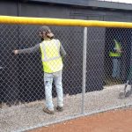 Four community service member repaint the dugout on the New Lexington High School softball field.